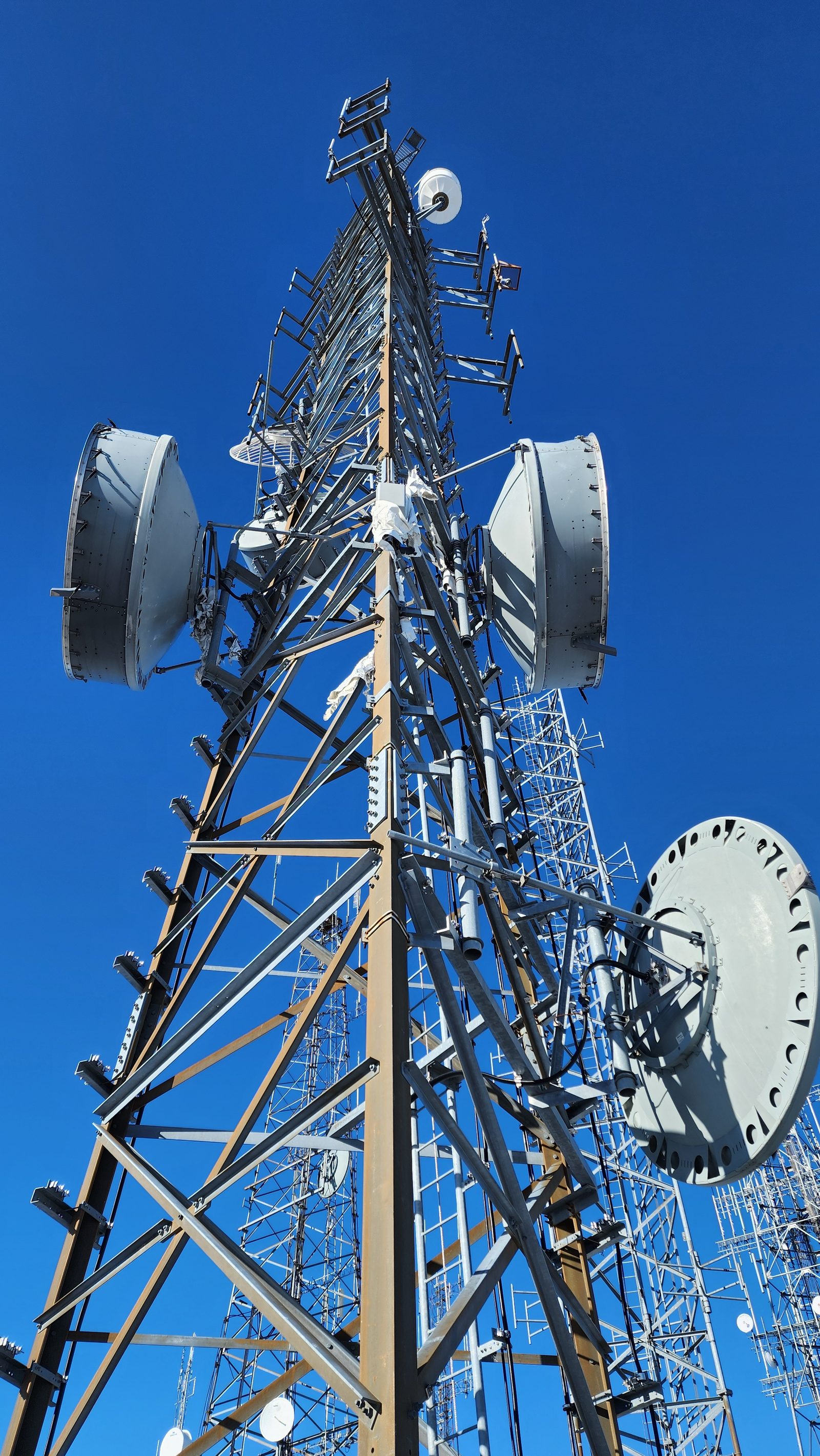 Microwave dishes on a lattice tower against a blue sky