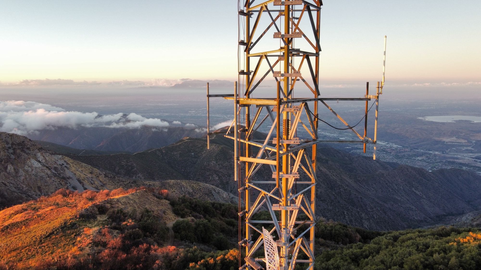 A broadcast tower in early light above the clouds
